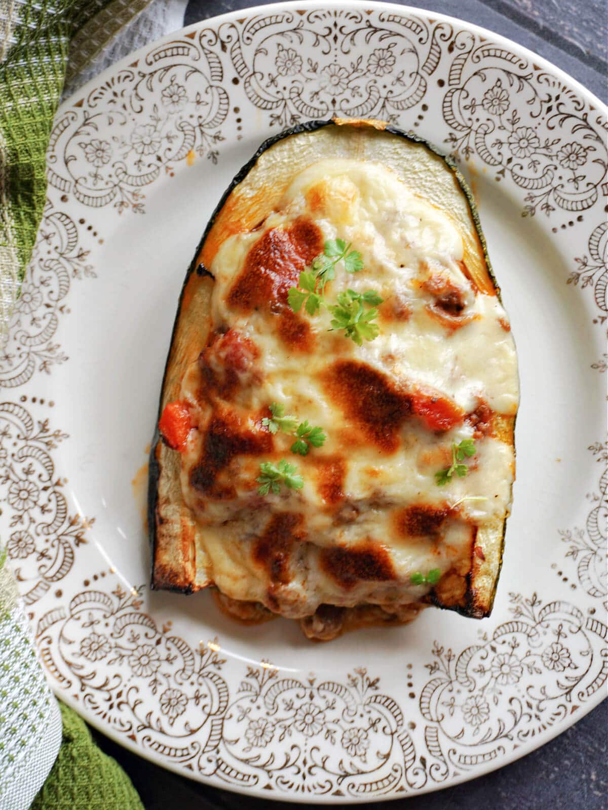 Overhead shoot of half of a marrow stuffed with bolognese sauce and topped with white sauce.