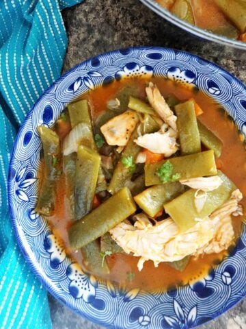 Overhead shoot of a blue bowl with green bean stew with shredded chicken