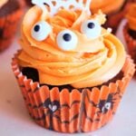 A Halloween cupcake with orange frosting and 3 edible eyes