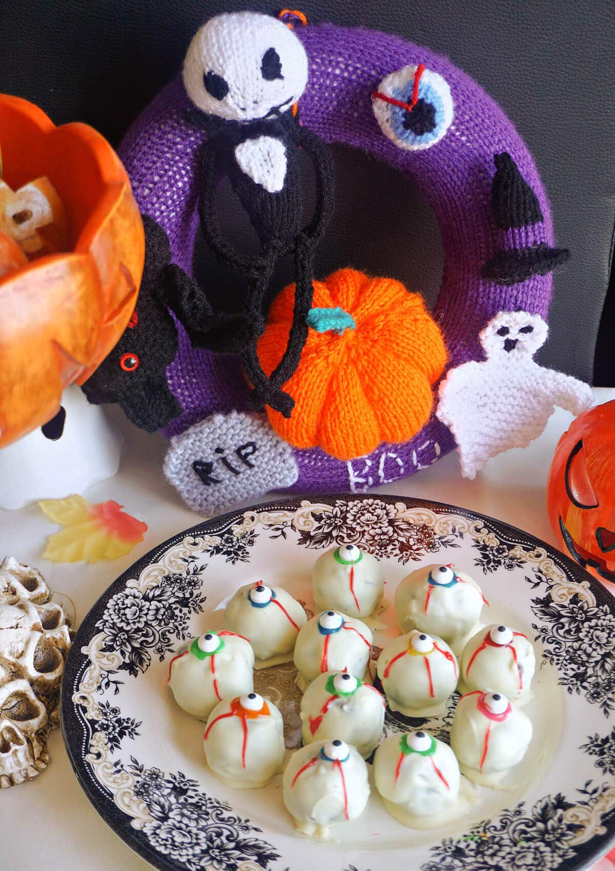 A plate with eyeball truffles surrounded by Halloween decorations.