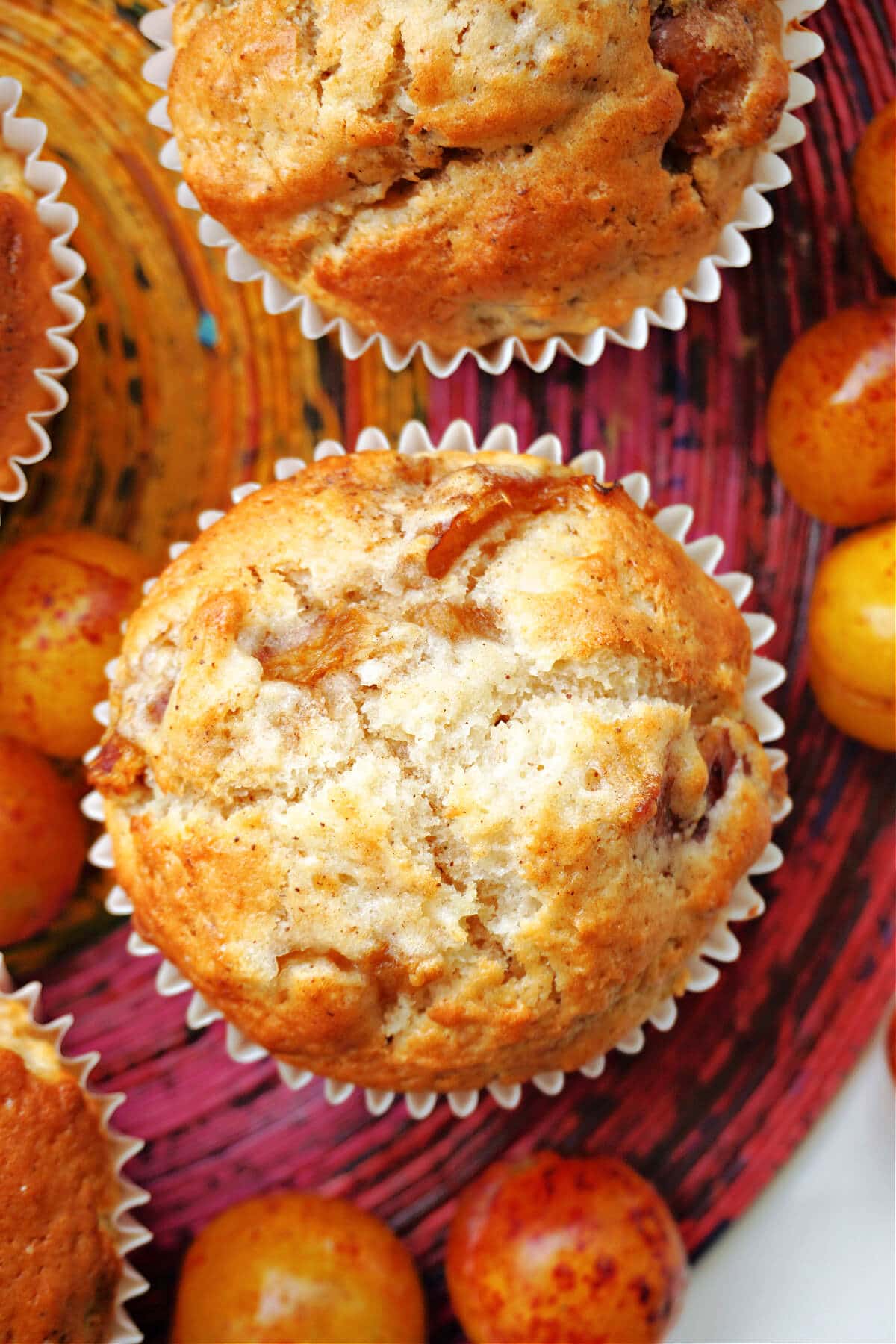 Overhead shoot of 2 plum muffins with cherry plums around them.