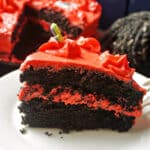 A slice of black velvet cake with red buttercream.