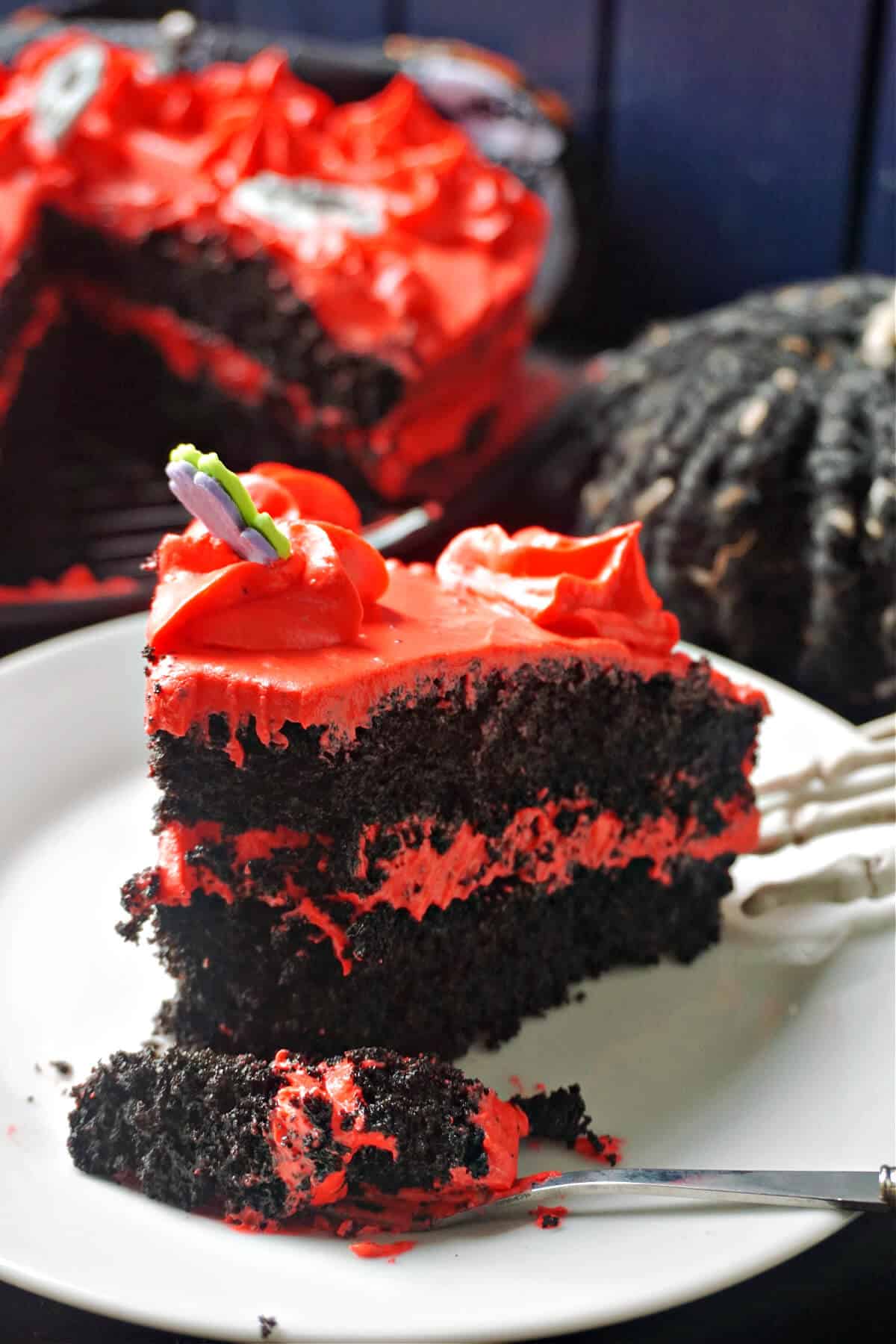 A slice of black velvet cake with red cream cheese icing.