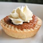 A white plate with a mini pumpkin pie topped with cream.