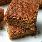A stack of 2 slices of ginger cake on a white plate.