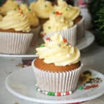 A gingerbread cupcake on a white plate with more cupcakes in the background