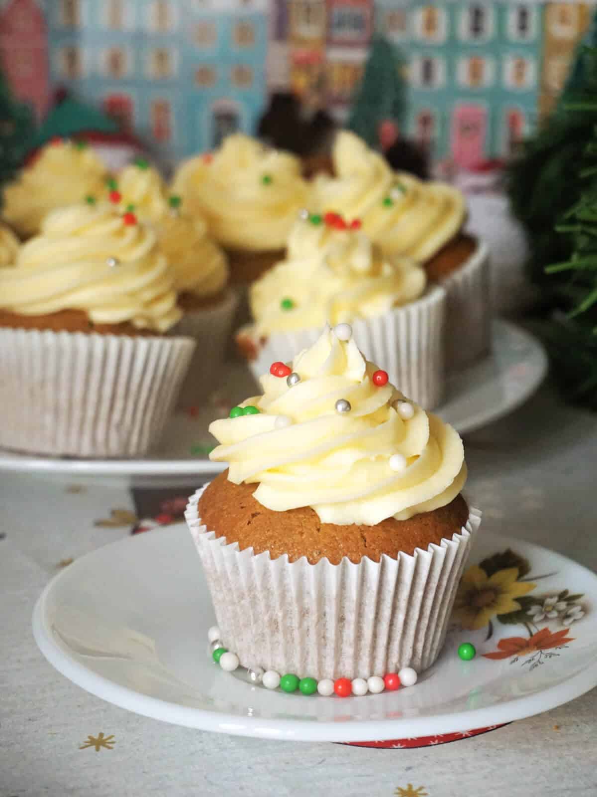 A gingerbread cupcake on a white plate with more cupcakes in the background.