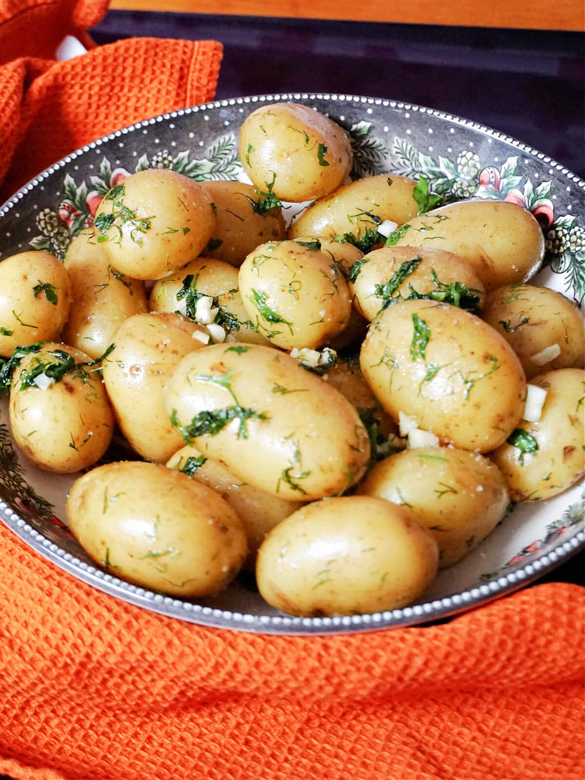 A bowl with boiled baby potatoes with garlic and herbs.