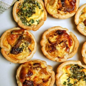 Close-up shoot of 8 mini quiches on a white plate
