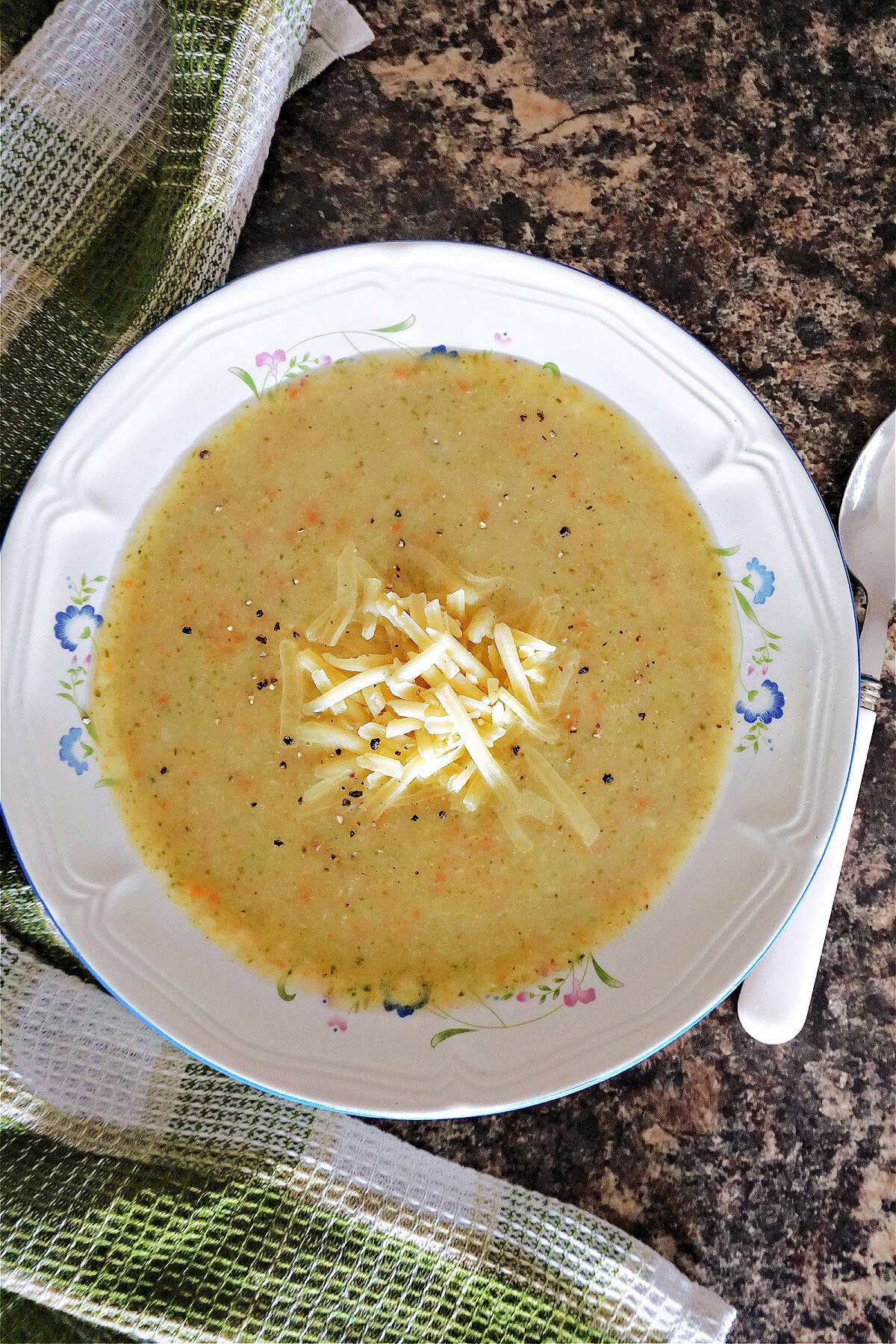 A white bowl with creamed soup garnished with grated cheese.