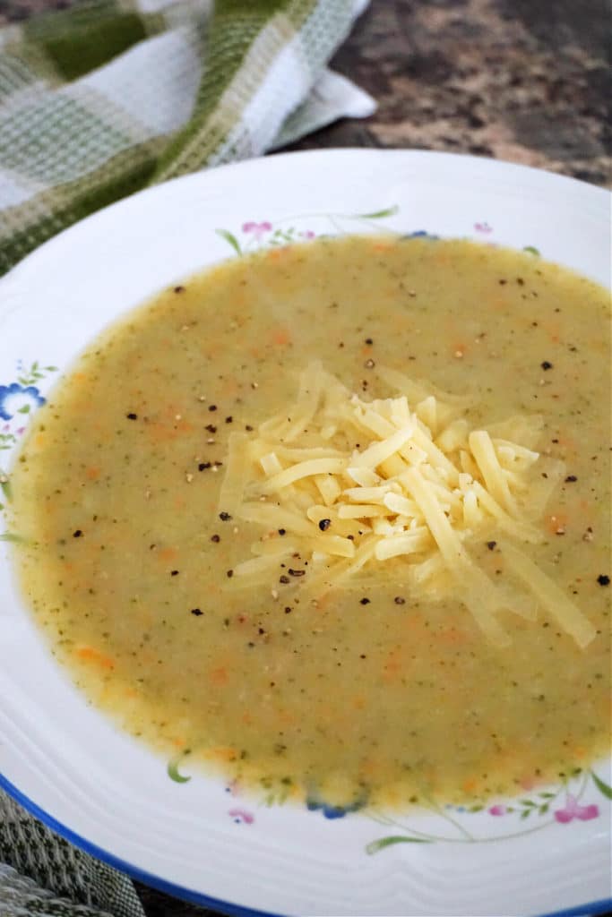 A white bowl with creamy soup garnished with grated cheese