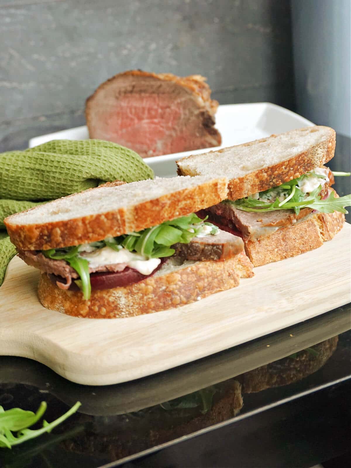 A beef sandwich on a wooden board.