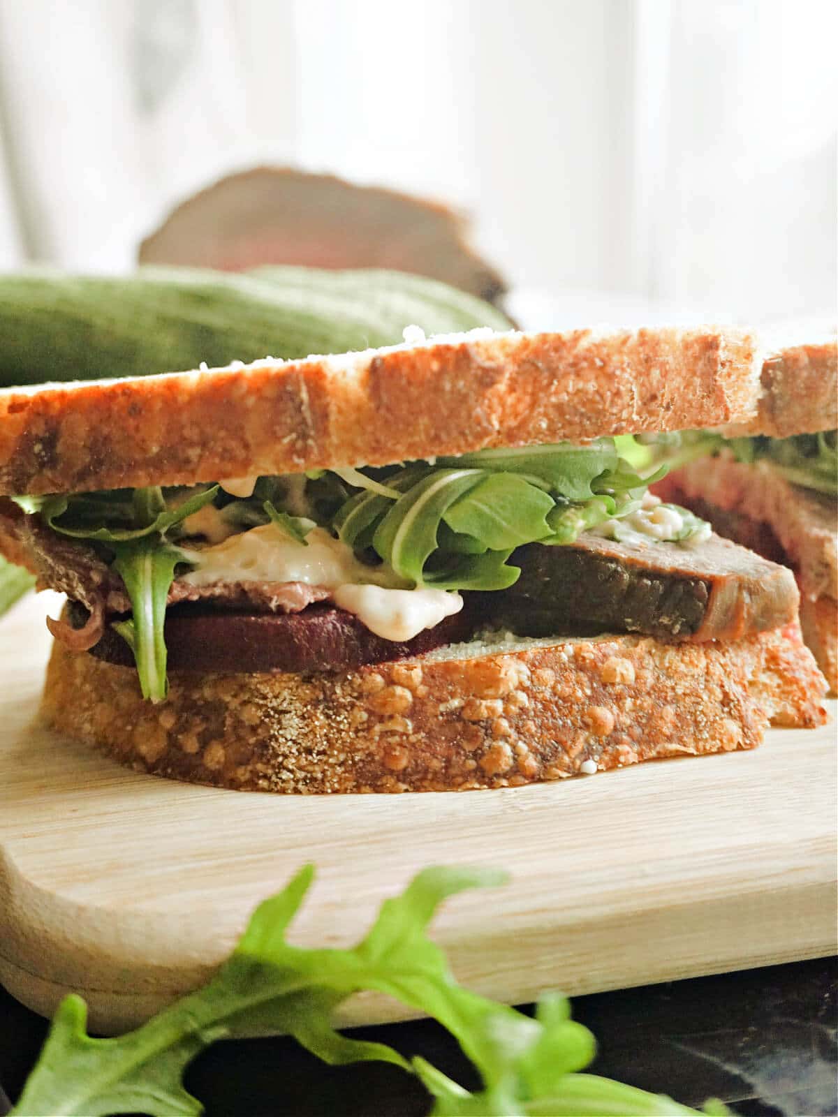 A beef sandwich on a wooden board.