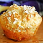 A muffin topped with oats on a wooden table.
