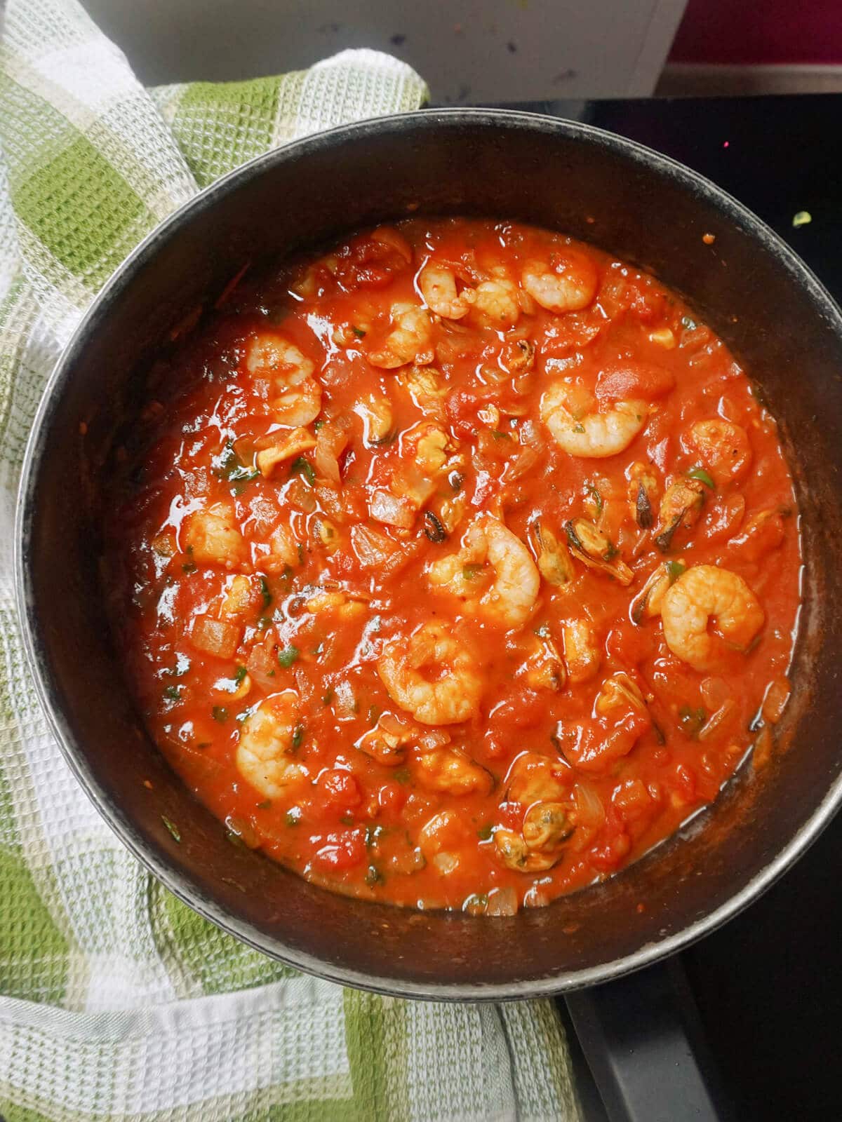 A pot with seafood stew in tomato sauce.