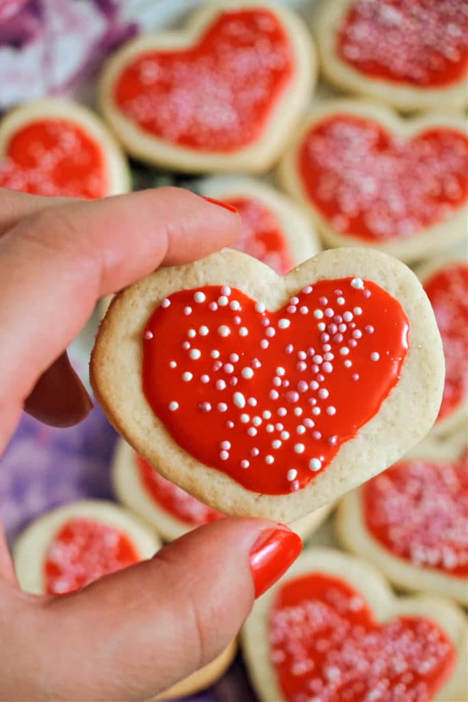 A heart-shape cookie shown on a background with more cookies