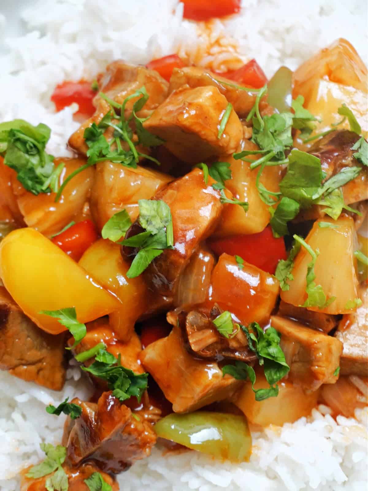 Close-up shoot of sweet and sour pork over a bed of rice.