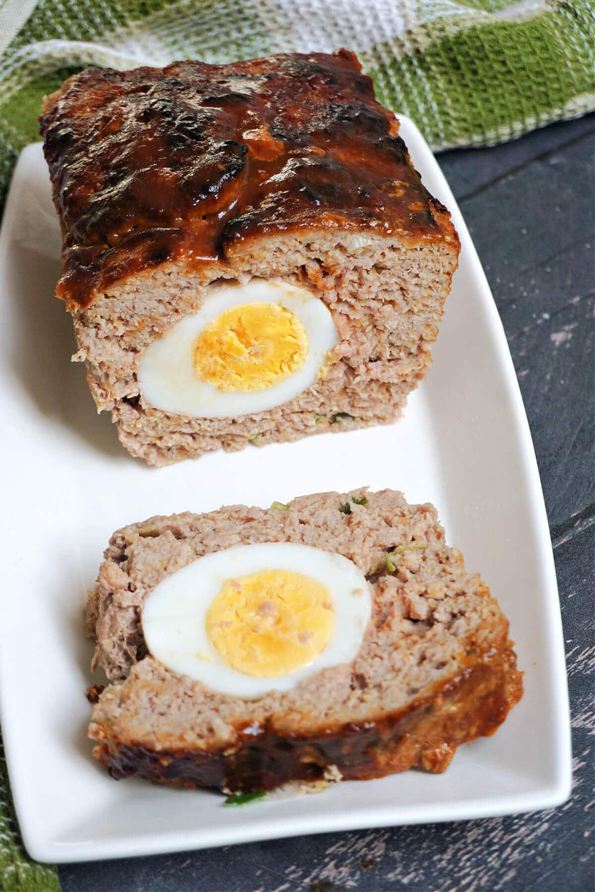 A sliced turkey meatloaf on a white rectangle plate.