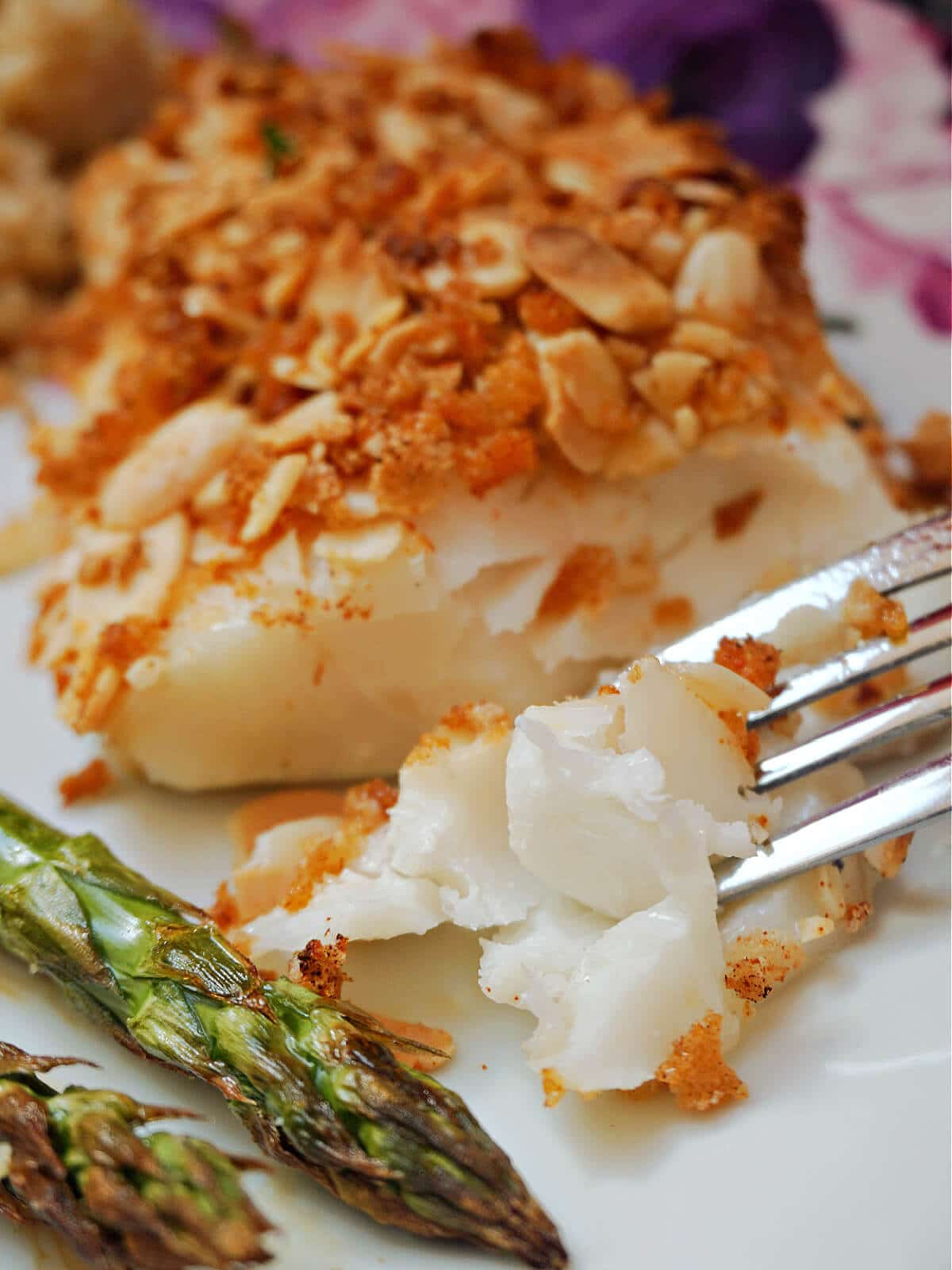 Close-up shoot of an almond-crusted cod on a white plate.