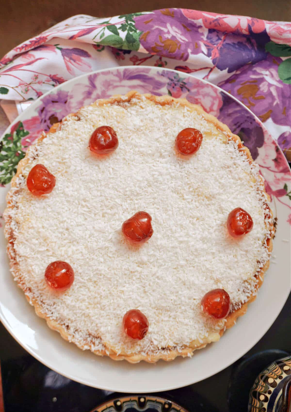 Overhead shoot of a white plate with a tart topped with maraschino cherries.