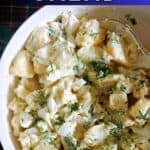 A white plate with potato and egg salad.