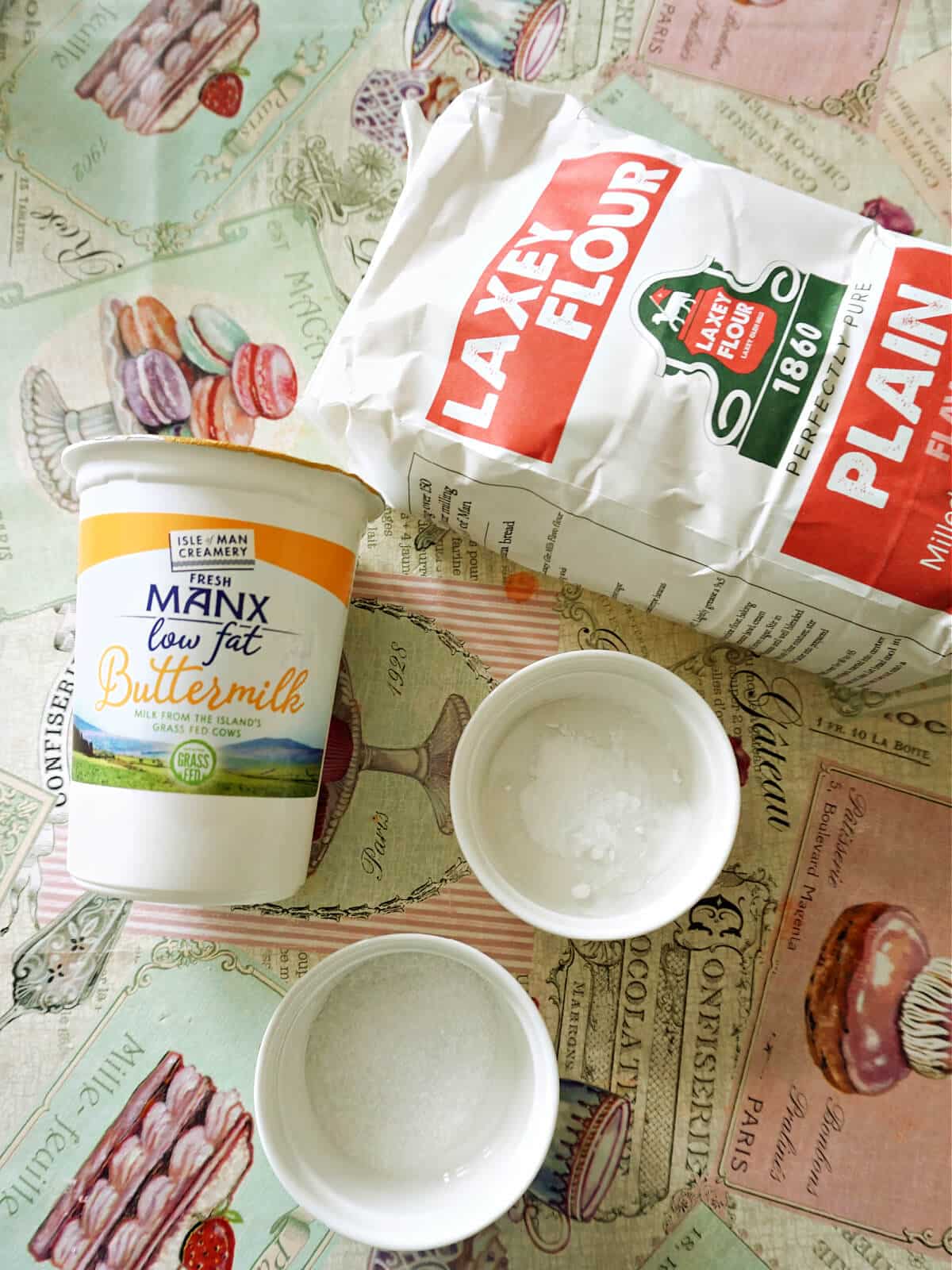 Overhead shoot of a tub of buttermilk, a package of flour, a ramekin with salt and one with bicarb of soda