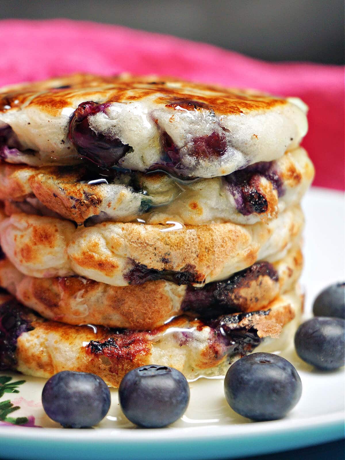 A pile of 5 pancakes with blueberries around.
