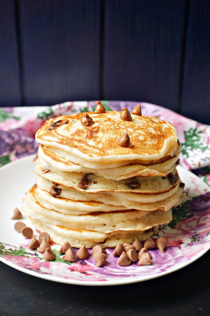 A stack of pancakes with chocolate chips on top and around