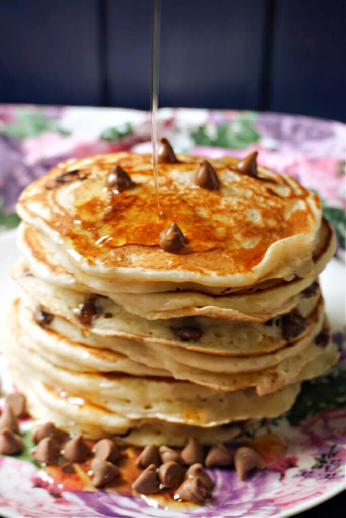 A stack of pancakes with maple syrup being drizzled over