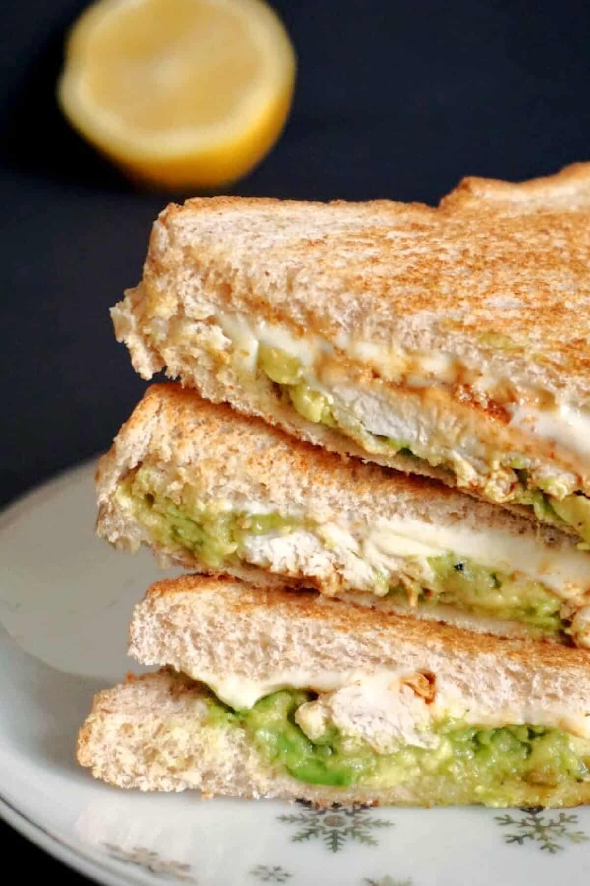 A stack of 3 sandwiches with chicken and avocado.