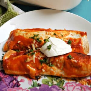 2 enchiladas on a plate topped with parsley and cream