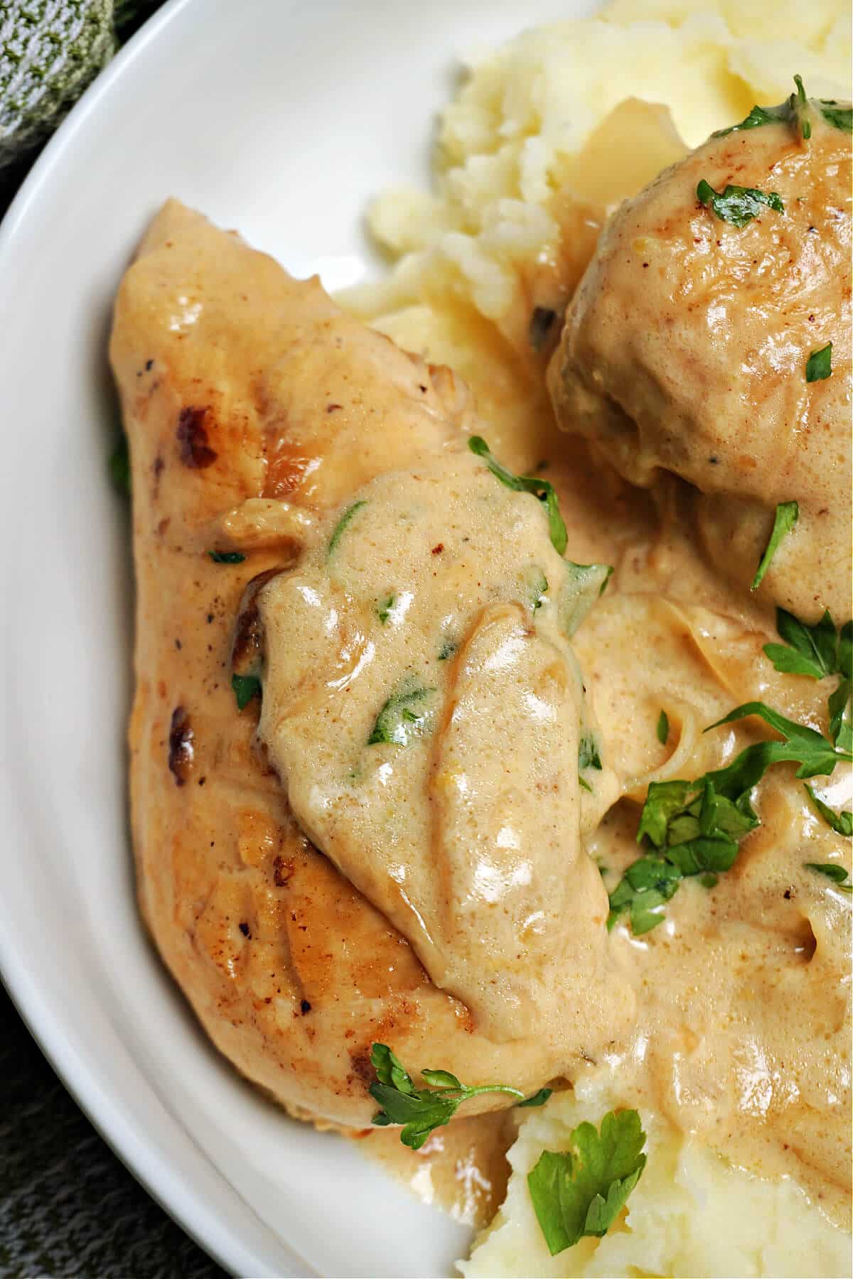 Close-up shoot of a chicken breast smothered in a lemon sauce on a bed of mash.