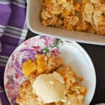 Overhead shoot of a plate with a portion of mango crumble and ice cream, and a dish with more crumble