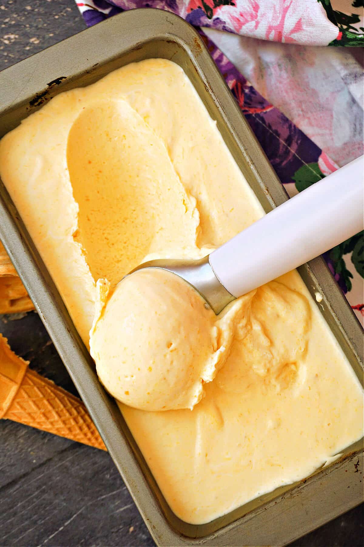 A tin with ice cream and a scooper.