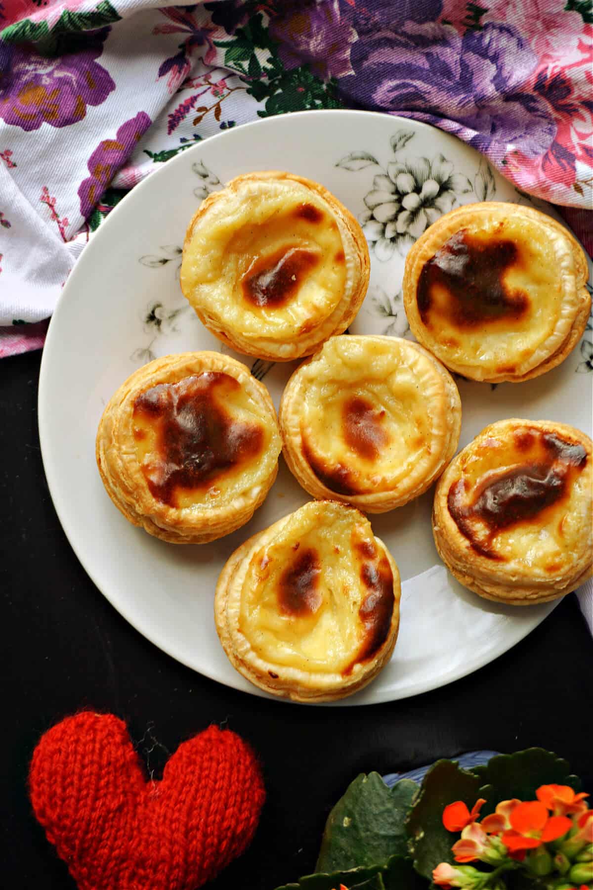 A white plate with 6 custard tarts.