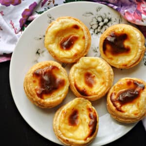 A white plate with 6 pasteis de nata.