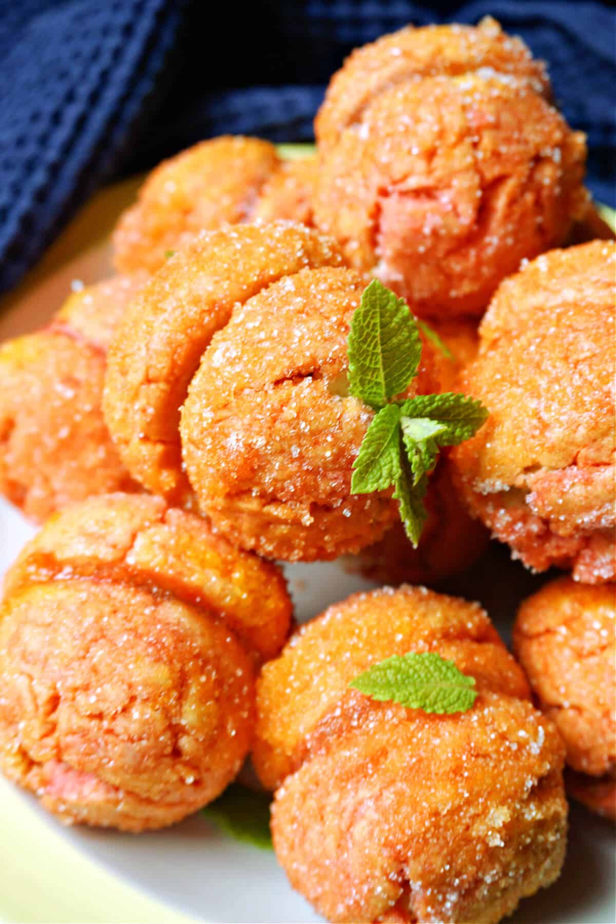 Close-up of peach-shaped cookies decaroated with mint leaves.