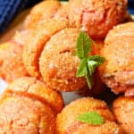 A white plate with peach-shaped cookies with mint leaves for decoration and a nacy blue tea towel in the background.