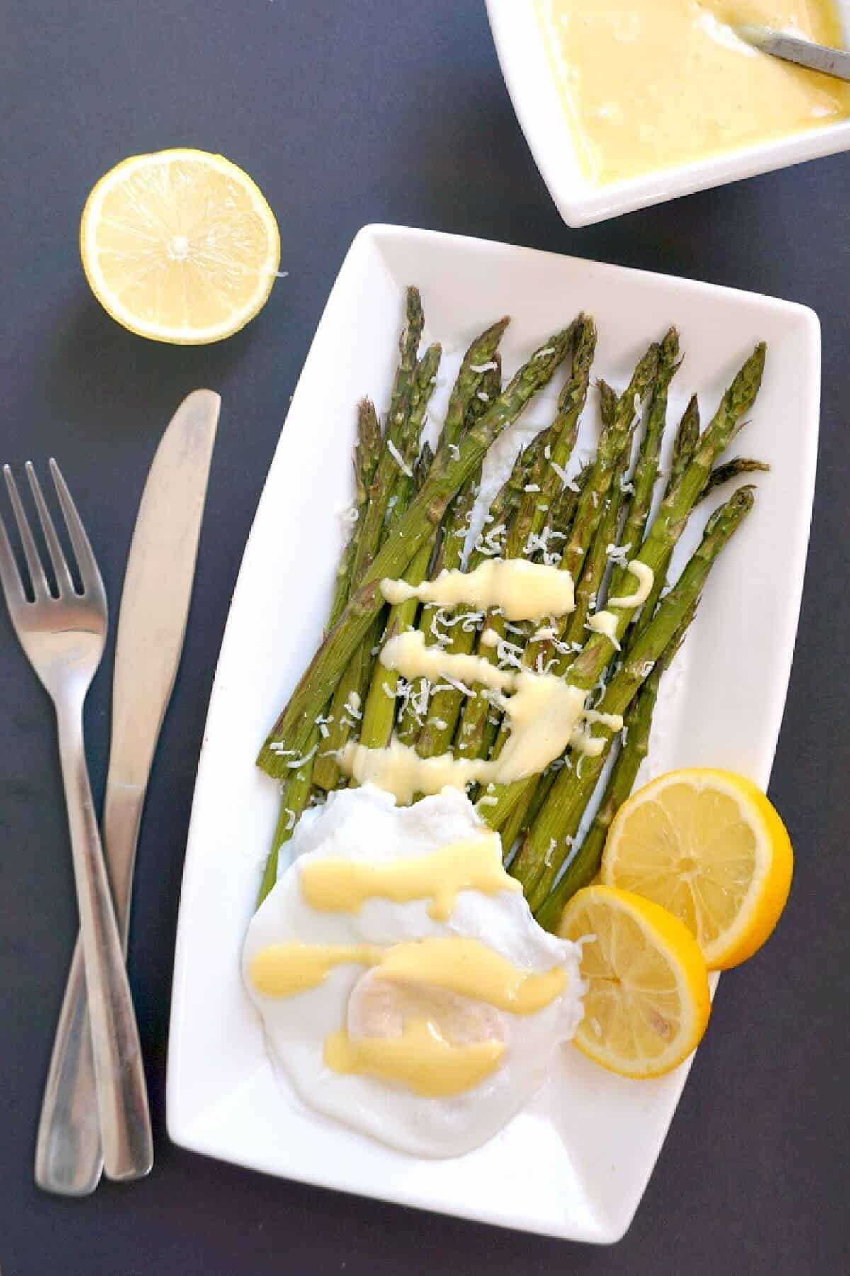 Overhead shoot of a white plate with grilled asparagus, poached egg and hollandaise sauce.