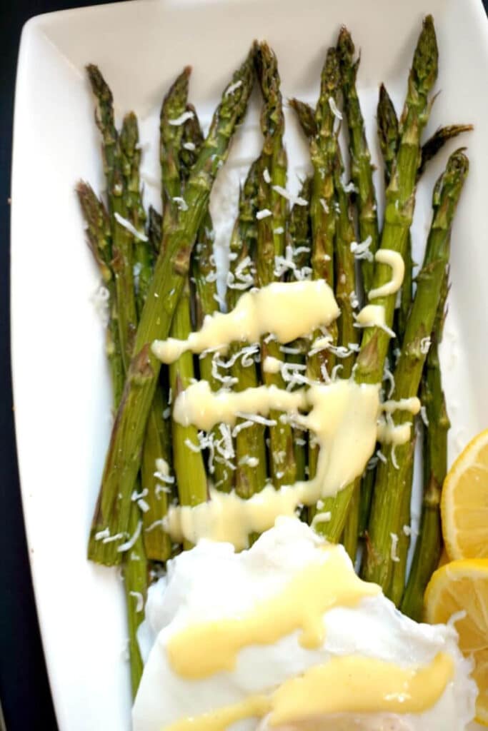 A white rectangle plate with grilled asparagus and hollandaise sauce