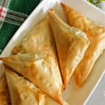 A white rectangle plate with Greek spanakopita triangles.