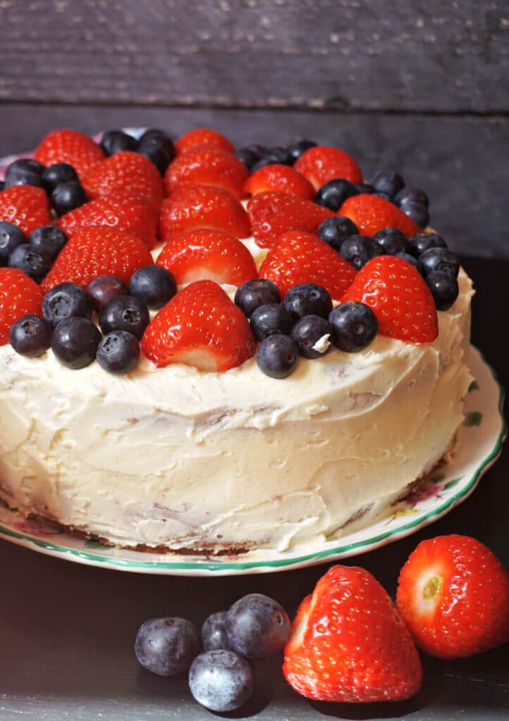 A vanilla cake topped with strawberries and raspberries