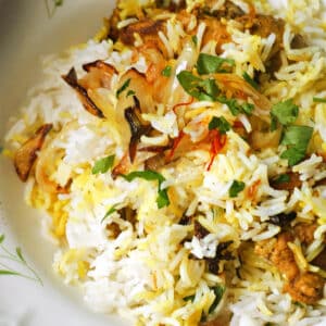 A white plate with chicken biryani.