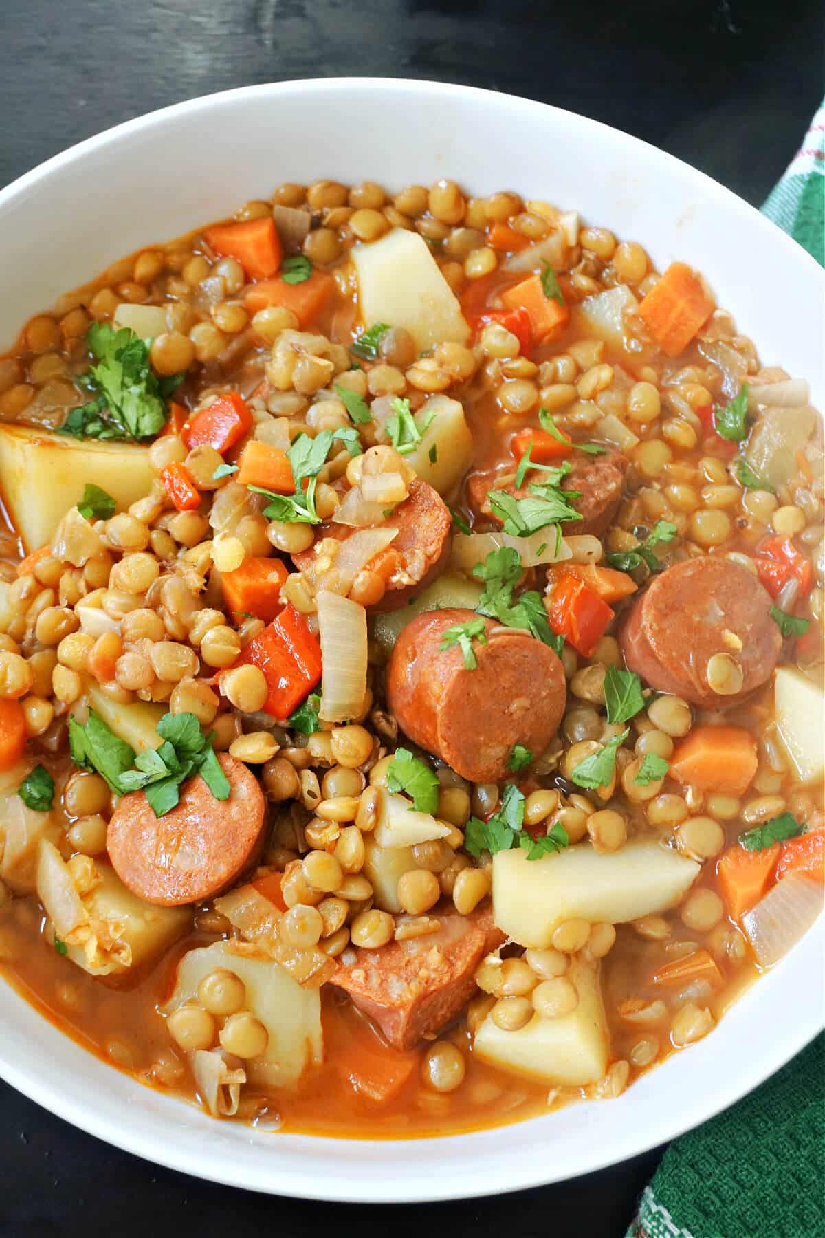 A white bowl with lentil and chorizo stew.