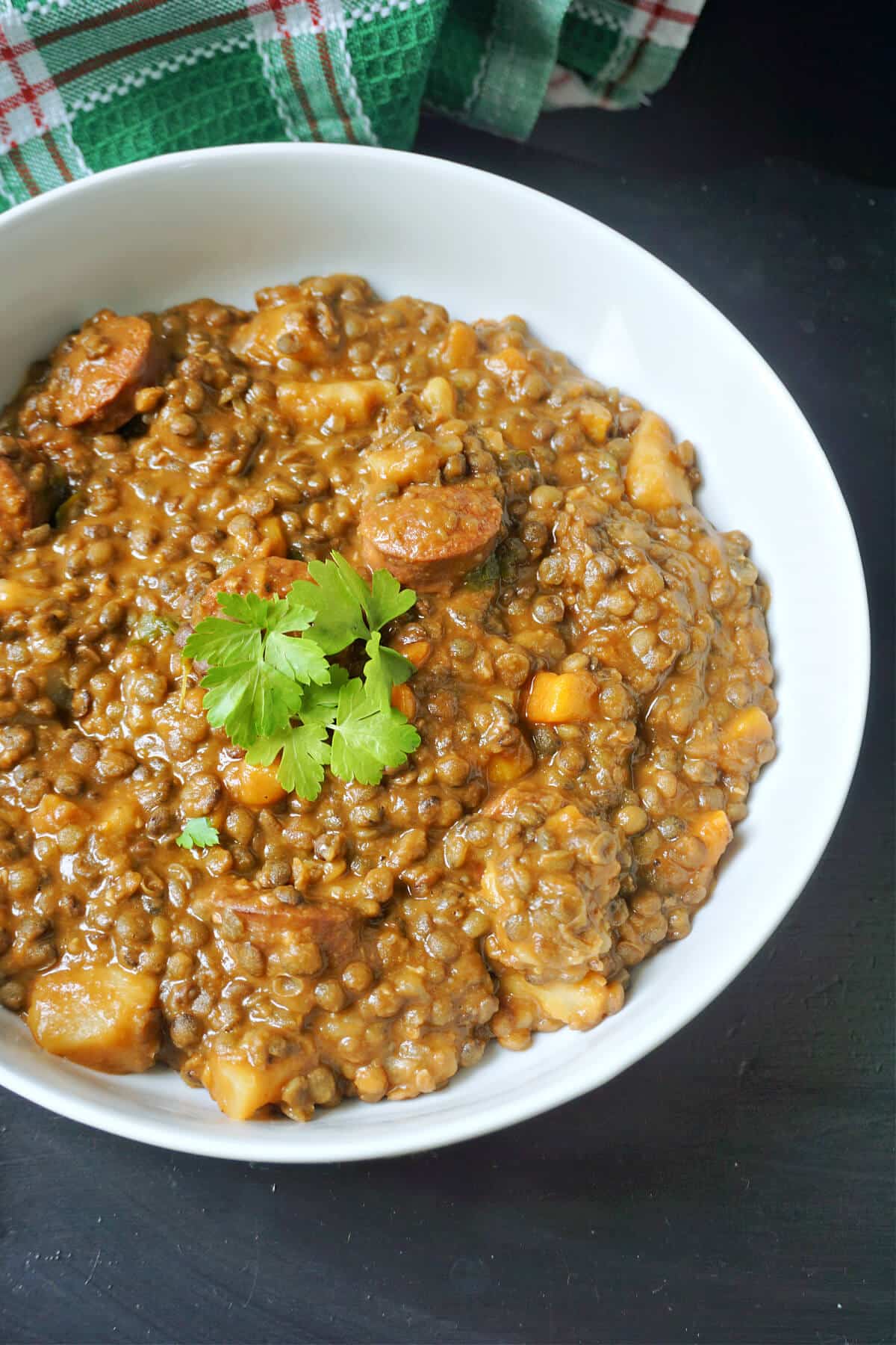 A white bowl with lentil stew with chorizo.