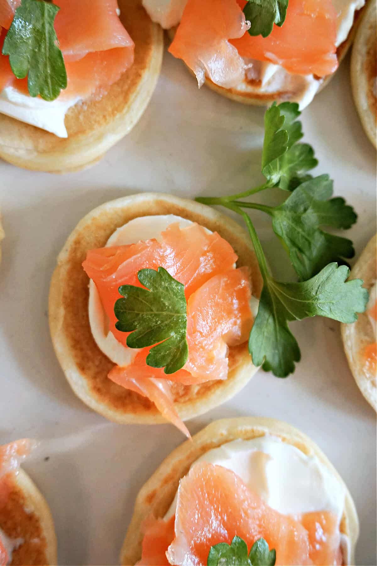 Blinis topped with cream cheese, smoked salmon and fresh parsley.