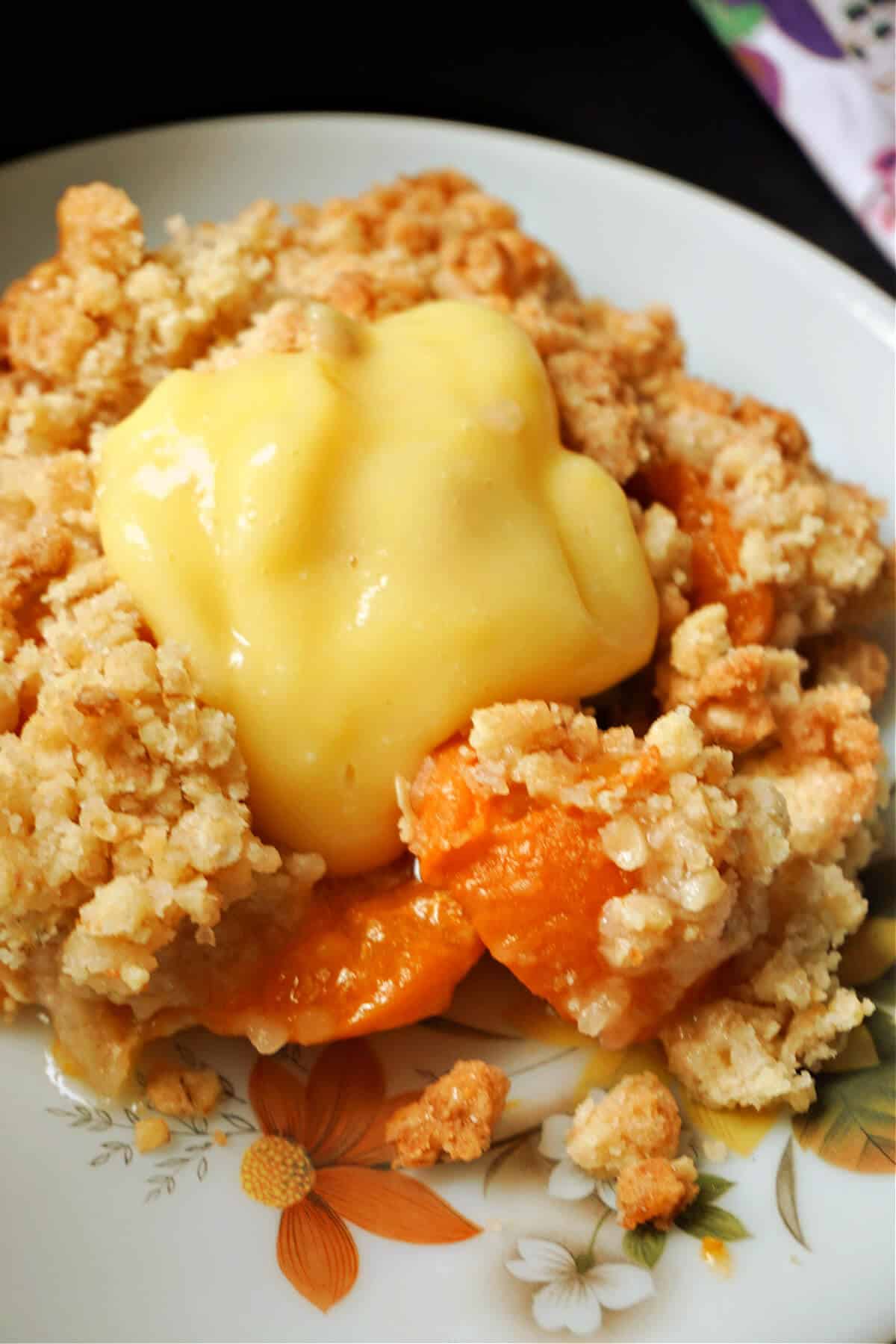 Close-up shoot of a portion of apricot crumble on a plate.