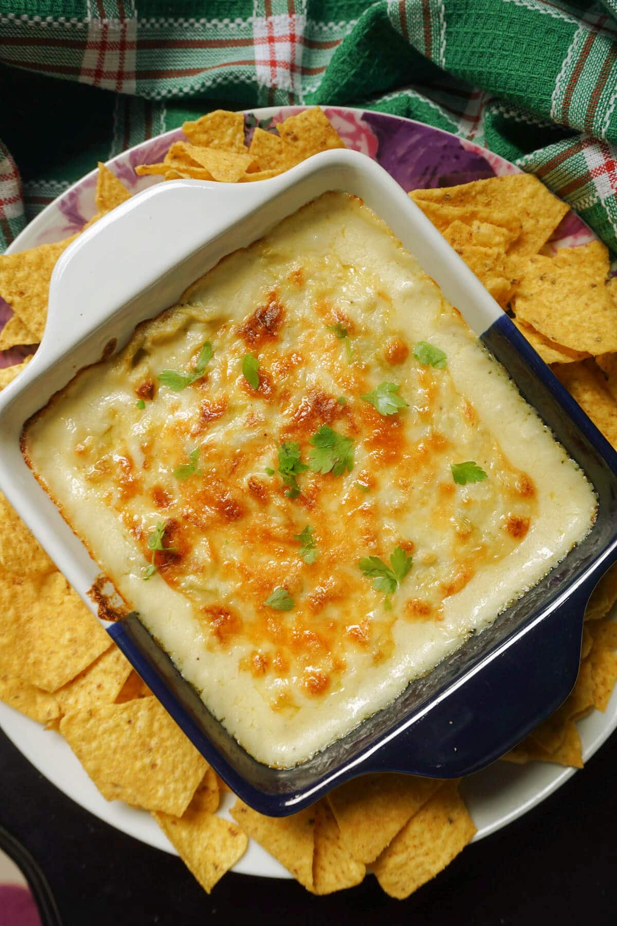 Overhead shoot of a dish with artichoke dip and nachos around