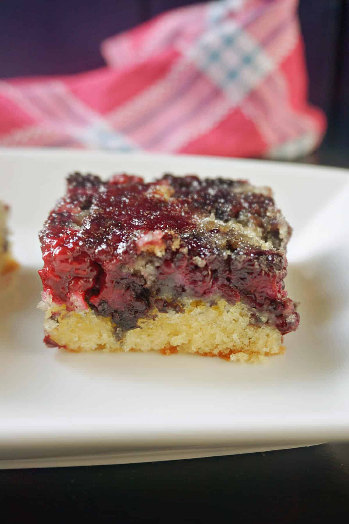 A slice of blackberry upside down cake on a white plate.