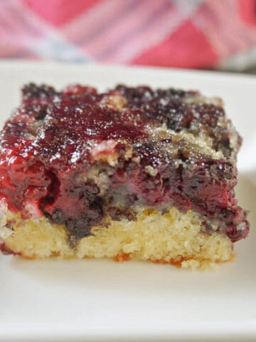 A slice of blackberry cake on a white plate.